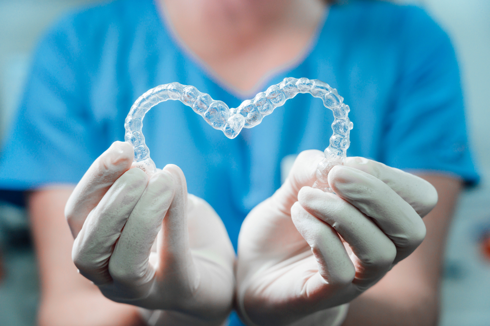 Dental Professional Holding Clear Aligners – Invisalign in Highlands A dental specialist wearing gloves displays two clear aligner trays, emphasizing the precision and customized fit of advanced orthodontic aligner therapy – Invisalign in Highlands.