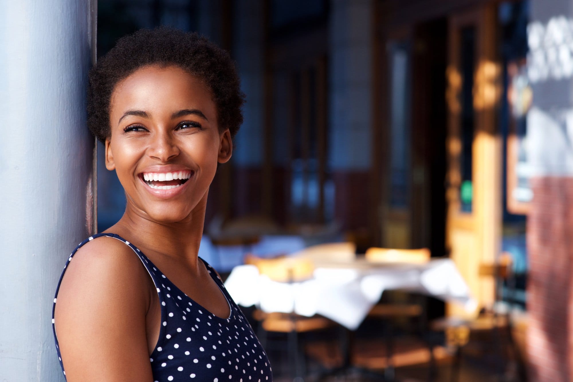Side portrait of smiling young black woman standing outside