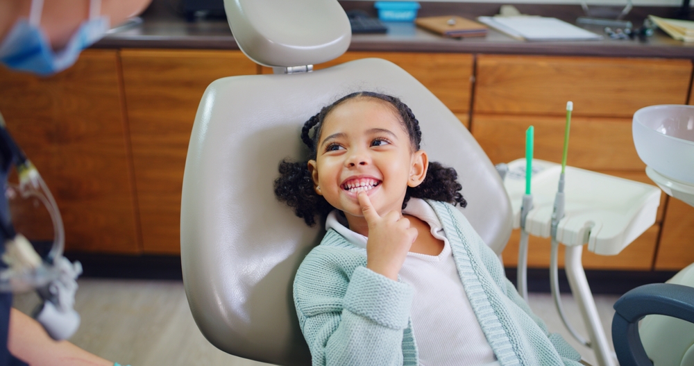 A young patient smiles confidently during a friendly dental visit, highlighting early orthodontic care and comfort for kids - Phase 1 Orthodontics