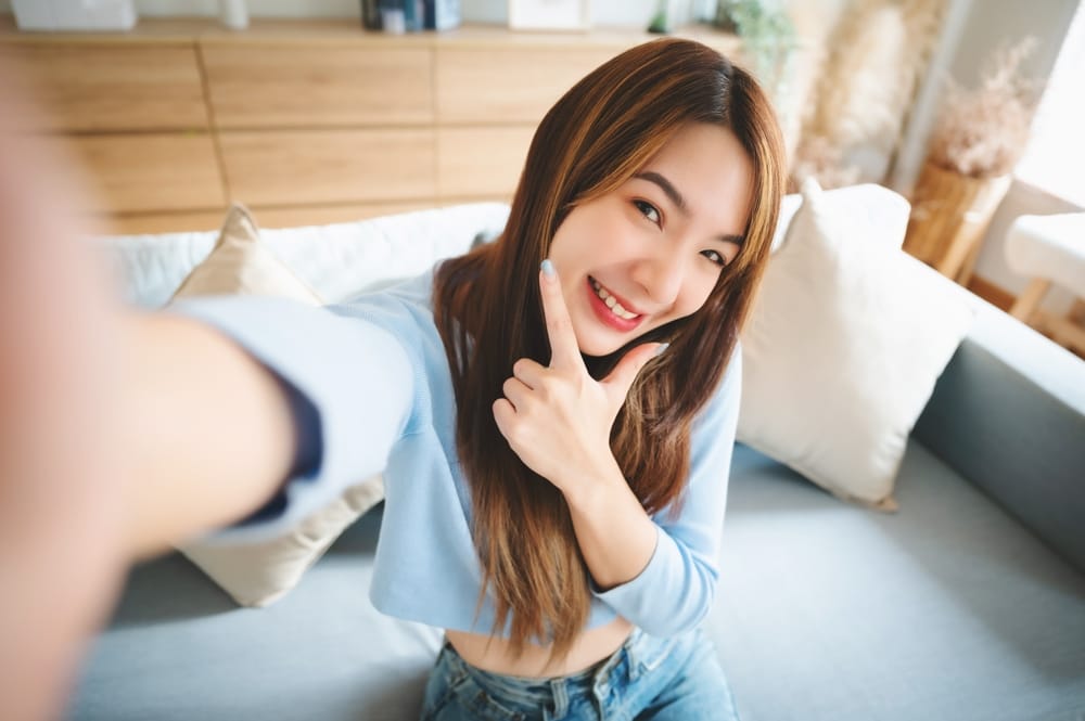 A cheerful woman poses for a selfie while pointing to her beautifully aligned teeth, highlighting the confidence that comes from professional orthodontic treatment – Highlands Ranch Orthodontics.